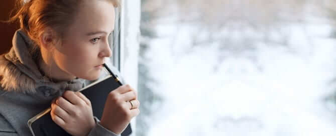 Girl contemplating with journal in hand