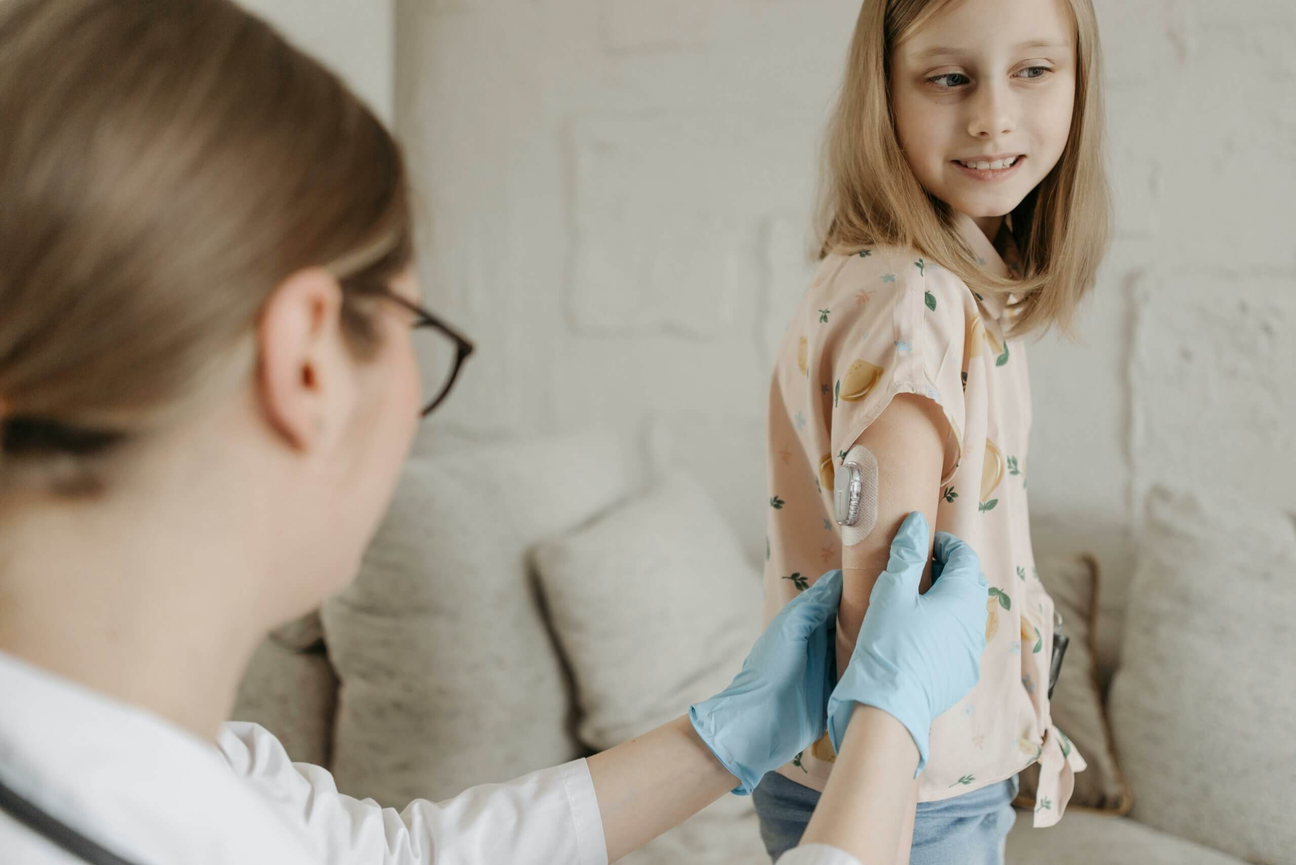 A health care professional assisting a child with an insulin pump