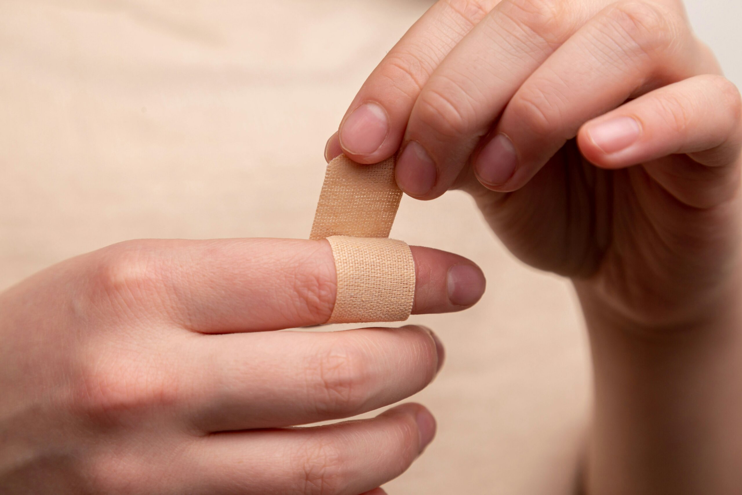 A person applying cloth medical tape to their finger